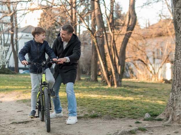 Padre enseñando a su hijo a andar en bicicleta vista larga