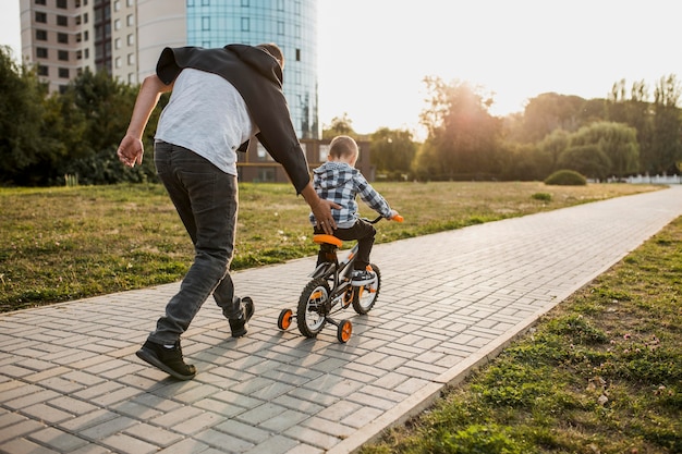 Foto gratuita padre enseñando a su hijo a andar en bicicleta