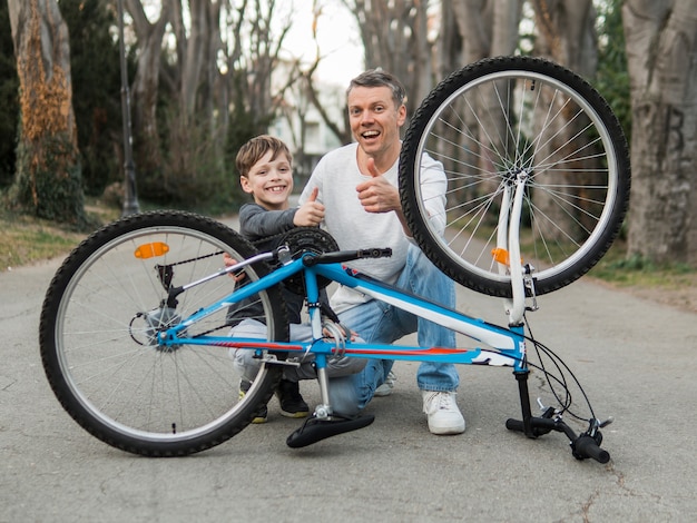 Padre enseñando a su hijo arreglando la bicicleta en el parque