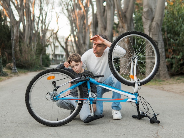 Padre enseñando a su hijo y arreglando la bicicleta