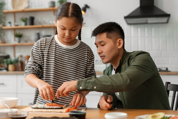 Padre enseñando a su hijo a hacer sushi