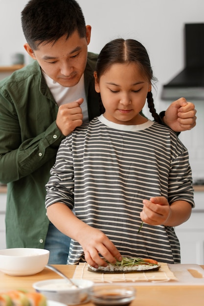 Padre enseñando a su hijo a hacer sushi