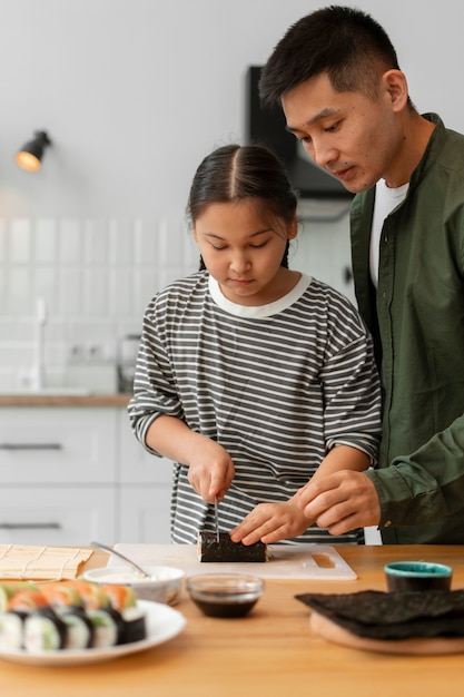 Padre enseñando a su hijo a hacer sushi