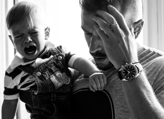 Padre estresado sosteniendo a un bebé llorando