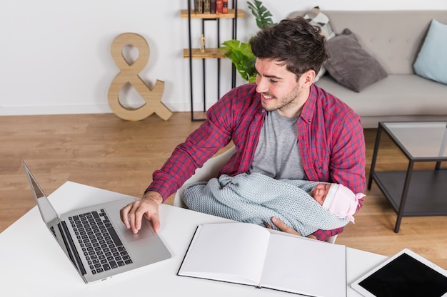 Padre feliz con el bebé usando la computadora portátil en el escritorio