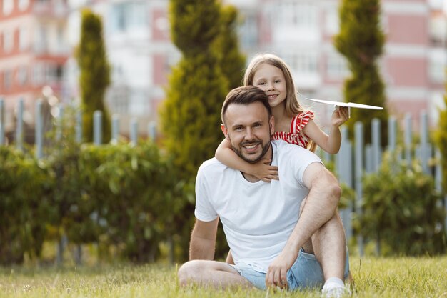 padre feliz jugando con aviones de hija al aire libre