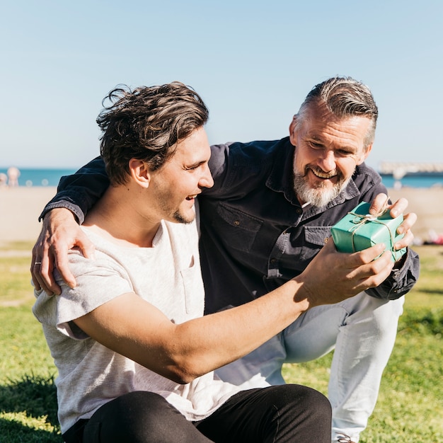 Padre feliz recibiendo regalo de hijo en la playa