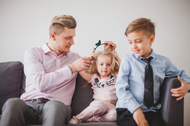 Padre feliz con sus hijos en el sofá