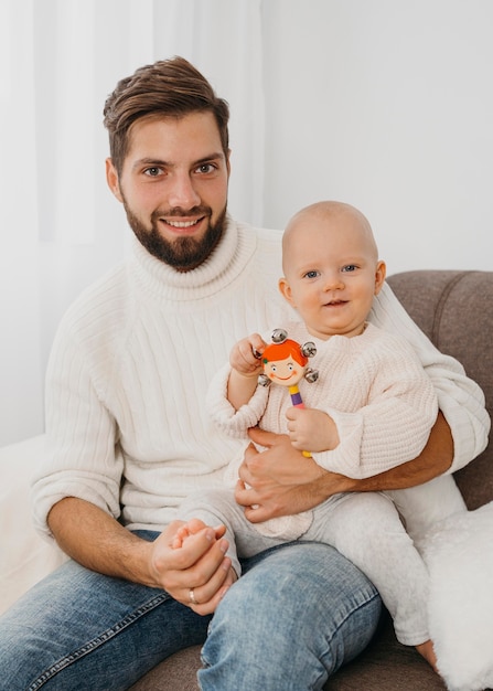 Foto gratuita padre guapo posando en el sofá con el bebé