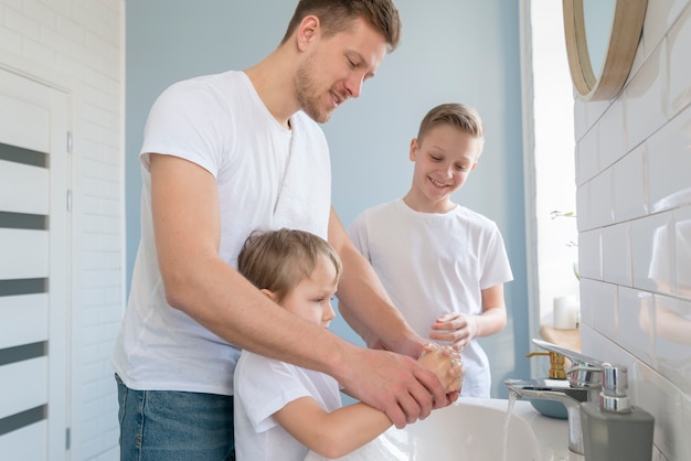 Padre con hermanos lavarse las manos en el baño.