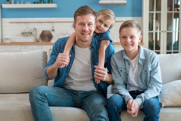 Padre con hermanos sentados en el sofá