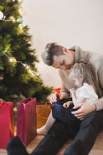 Padre con hija al lado de árbol de navidad