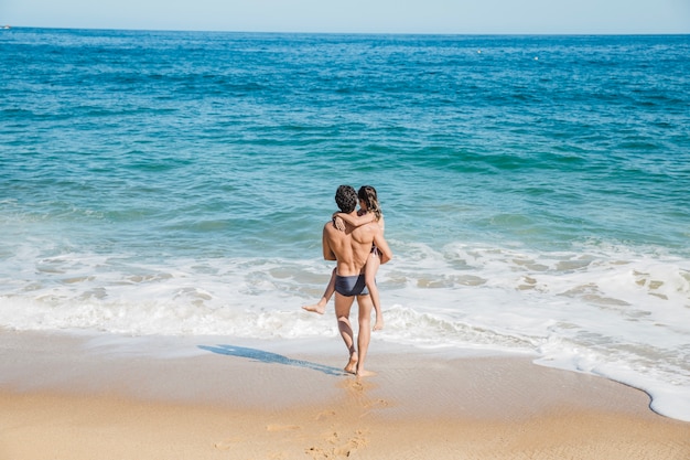 Padre con hija en el brazo andando hacia el agua