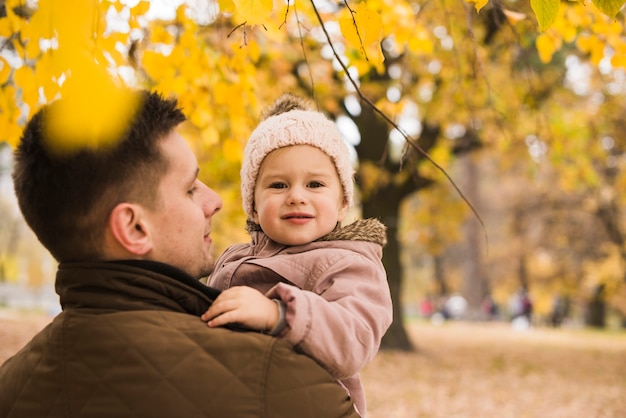 Padre con hija en manos en el parque de otoño