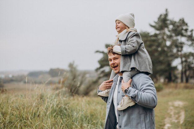 Padre con hija pequeña juntos en clima otoñal divirtiéndose