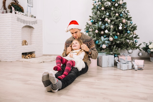 Padre con hija en piernas celebrando navidad en casa