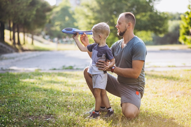Foto gratuita padre con hijo jugando con avión de juguete en el parque