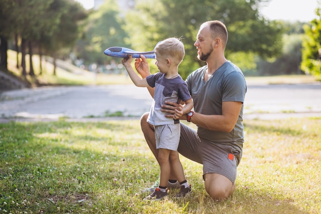 Padre con hijo jugando con avión de juguete en el parque