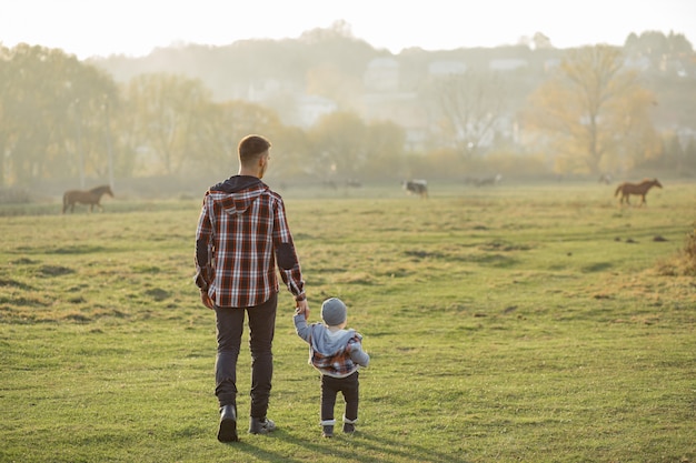 Padre con hijo pequeño caminando en un campo de mañana