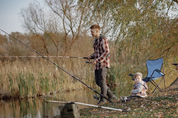 Padre con hijo pequeño cerca del río en una mañana de pesca