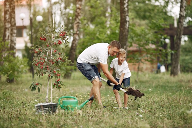 Padre con hijo pequeño están plantando un árbol en un patio