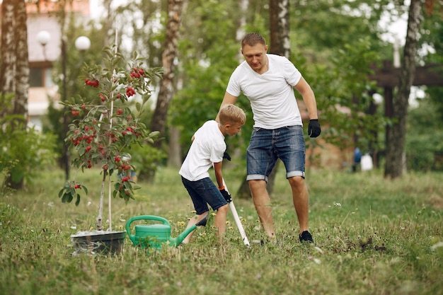 Foto gratuita padre con hijo pequeño están plantando un árbol en un patio