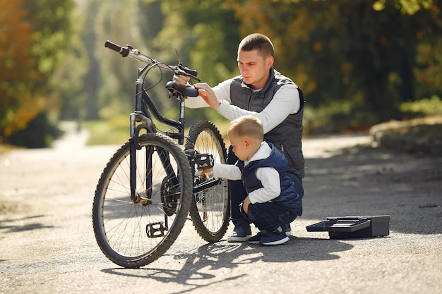 Padre con hijo repare la bicicleta en un parque