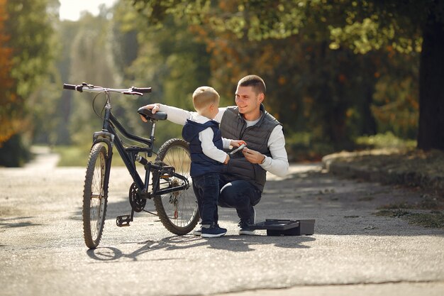 Padre con hijo repare la bicicleta en un parque