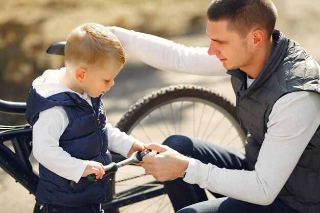 Padre con hijo repare la bicicleta en un parque