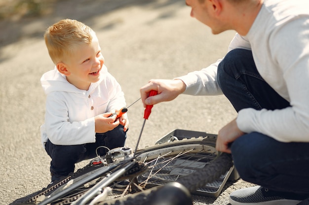 Padre con hijo repare la bicicleta en un parque