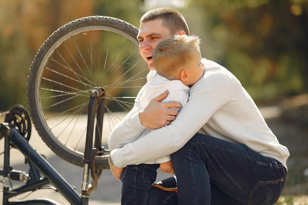 Padre con hijo repare la bicicleta en un parque