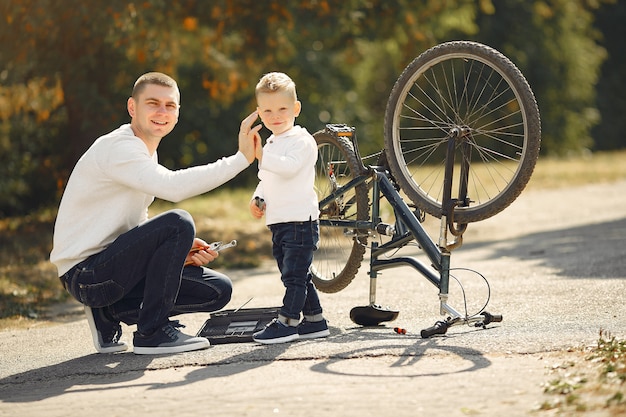 Padre con hijo repare la bicicleta en un parque