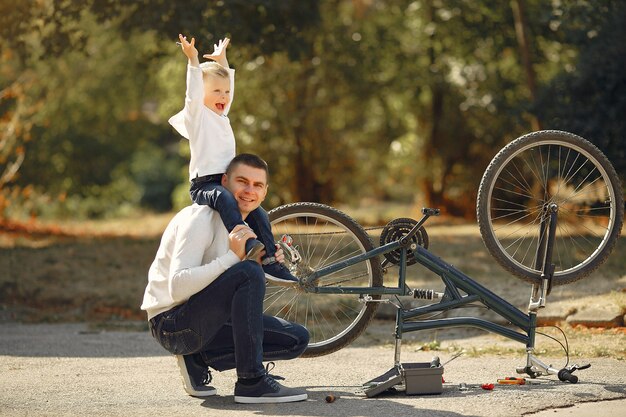 Padre con hijo repare la bicicleta en un parque