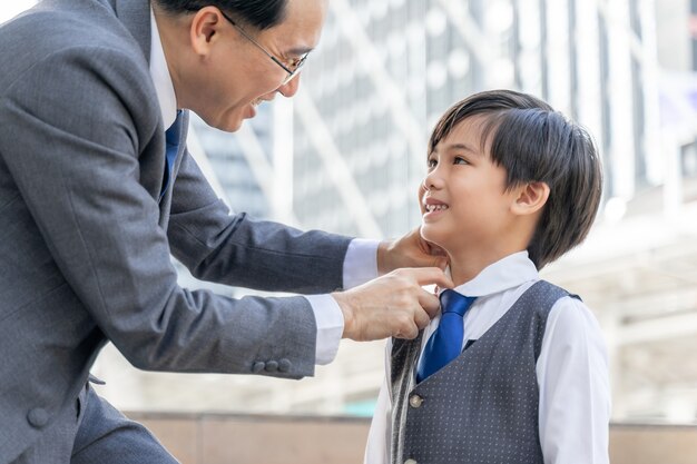 Padre hizo el cuello del traje para su hijo en el distrito de negocios urbano.