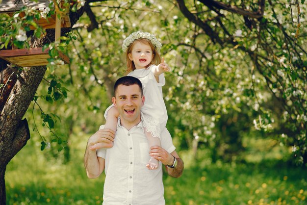 un padre joven y guapo jugando con su pequeña hija en el parque de verano