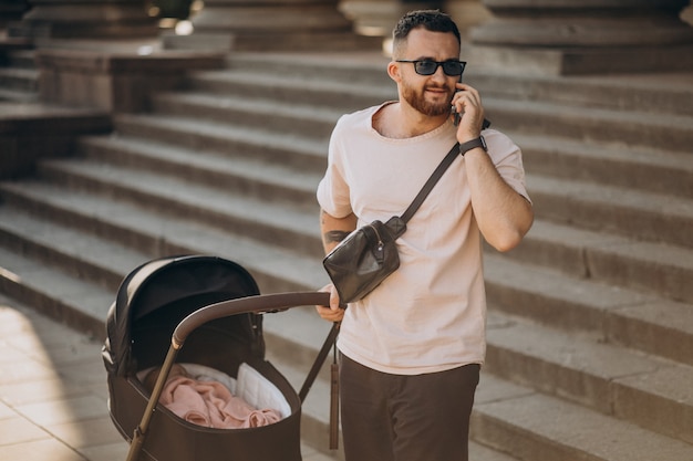 Padre joven saliendo con su bebé en un cochecito de bebé