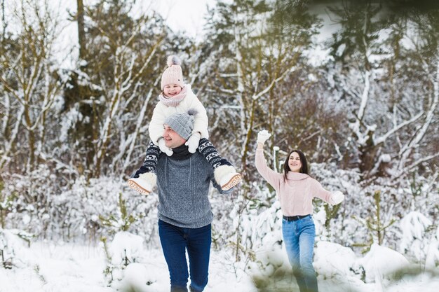 Padre jugando con hijas en el bosque de invierno