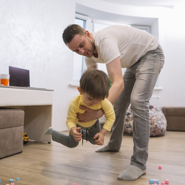 Padre jugando y sosteniendo a su hijo