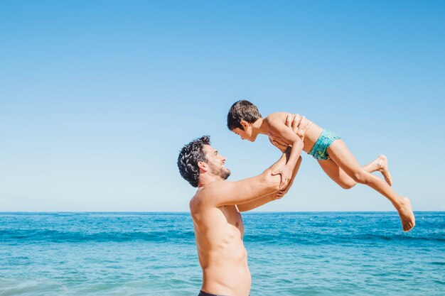 Padre levantando hijo por la orilla