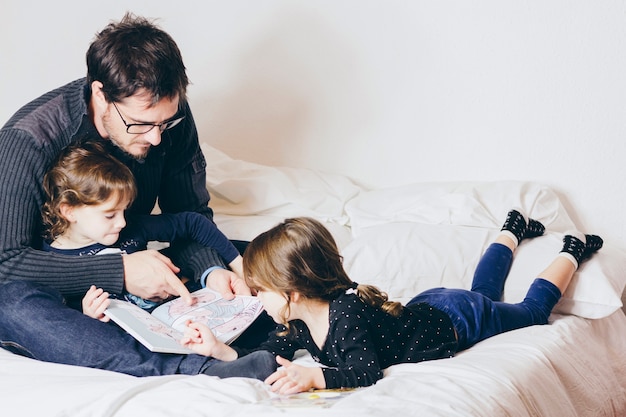 Padre leyendo libro con chicas lindas