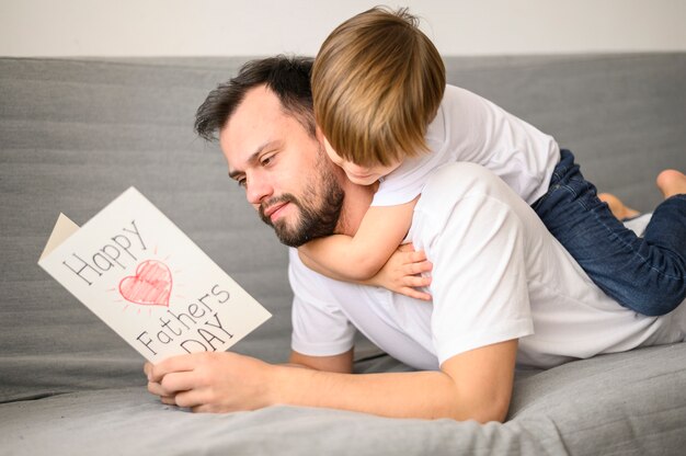 Padre leyendo la tarjeta de felicitación en el sofá