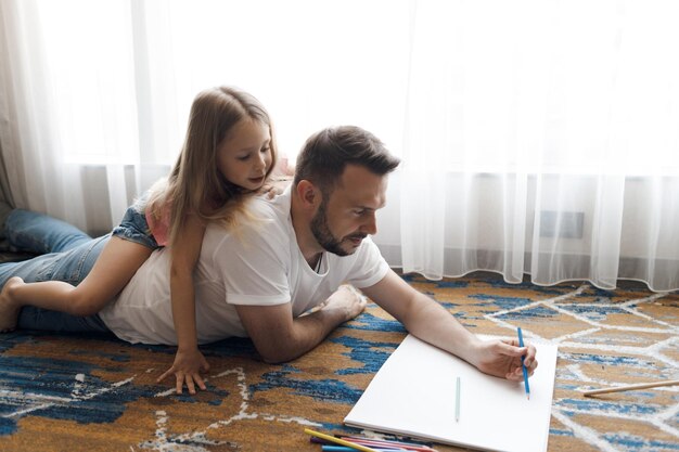 padre con linda hijita dibujando en casa