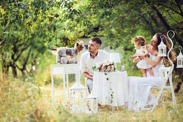 Padre, madre e hija juntos en el picnic en el jardín