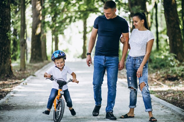 Padre con madre enseñando a su pequeño hijo a andar en bicicleta