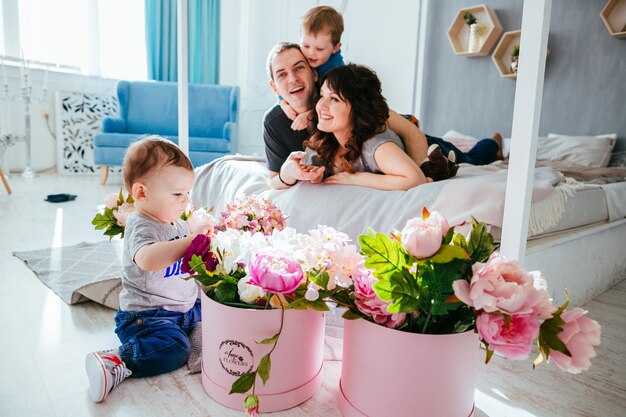 El padre, la madre y el hijo se encuentran en la cama y el pequeño hijo jugando con flores