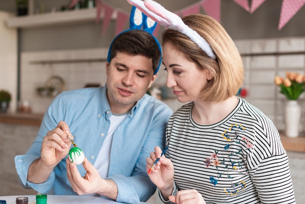 Padre y madre pintando huevos para pascua