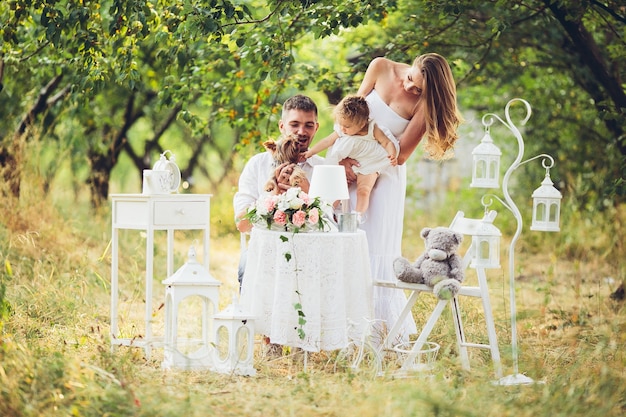 Padre y madre con su hija en mitad del campo con mesa y sillas blancas