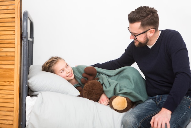 Padre metiendo hija en cama