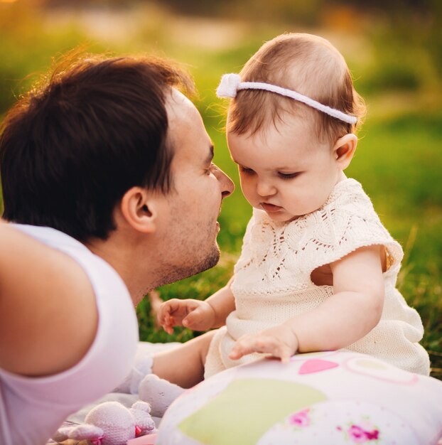 El padre miente antes de la niña en el césped