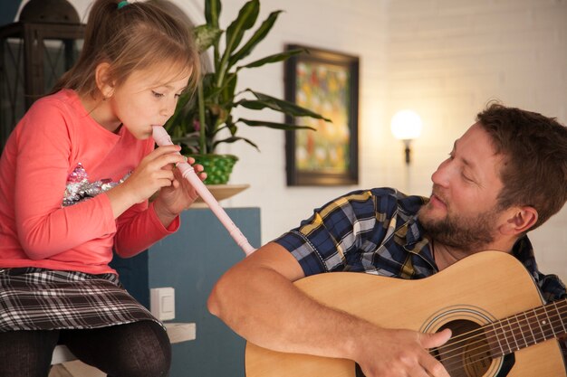 Padre mirando a su hija mientras toca la flauta